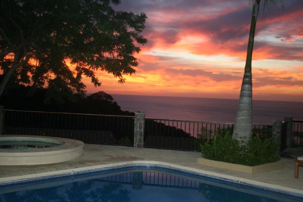 View of sunset, hot tub and pool