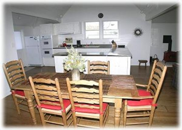 A large dining table is next to the kitchen 